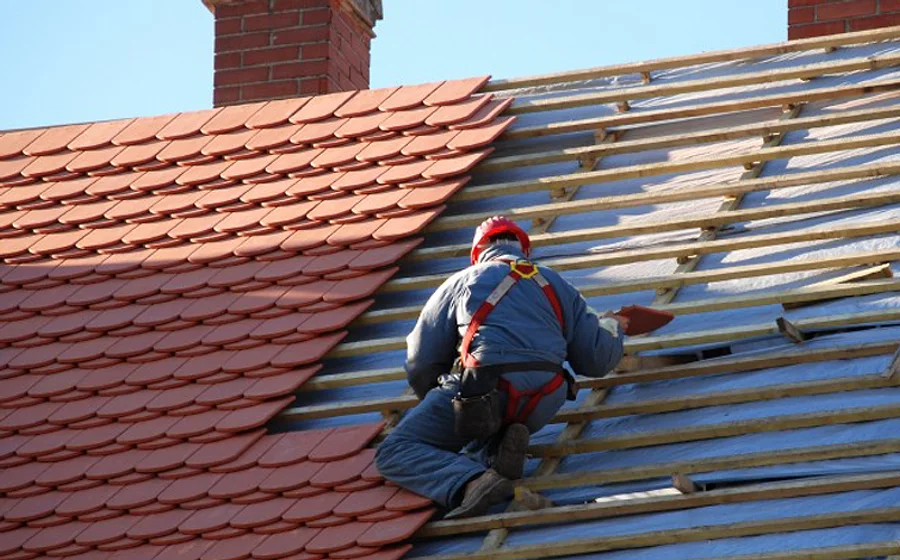 A roofer re-tiling a roof during a full re-roof